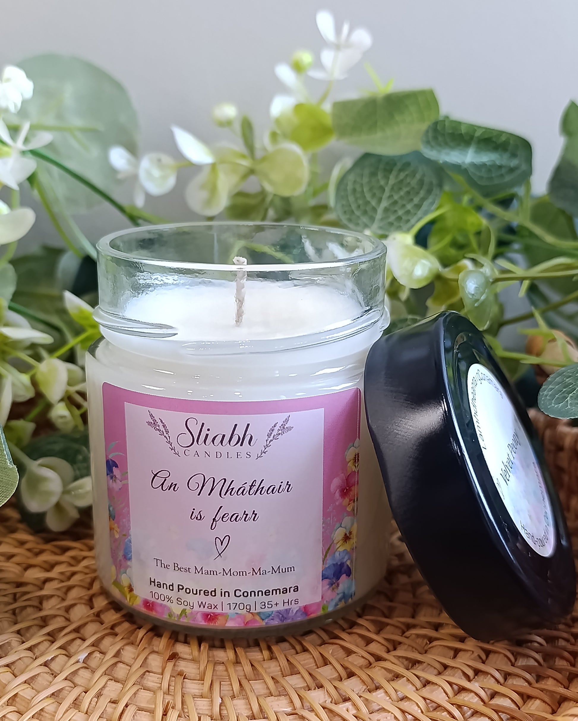 Scented soy wax candle in a glass jar with black lid. An mháthair is fearr - the best mam- label on it. 