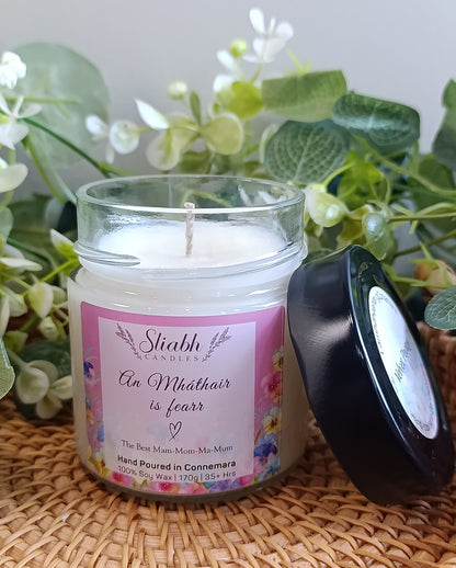 Scented soy wax candle in a glass jar with black lid. An mháthair is fearr - the best mam- label on it. 