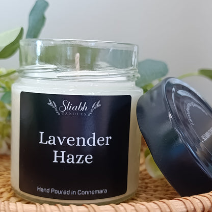 Candle jar labeled 'Lavender Haze' by Stiabh Candles on a woven surface with a plant in the background.