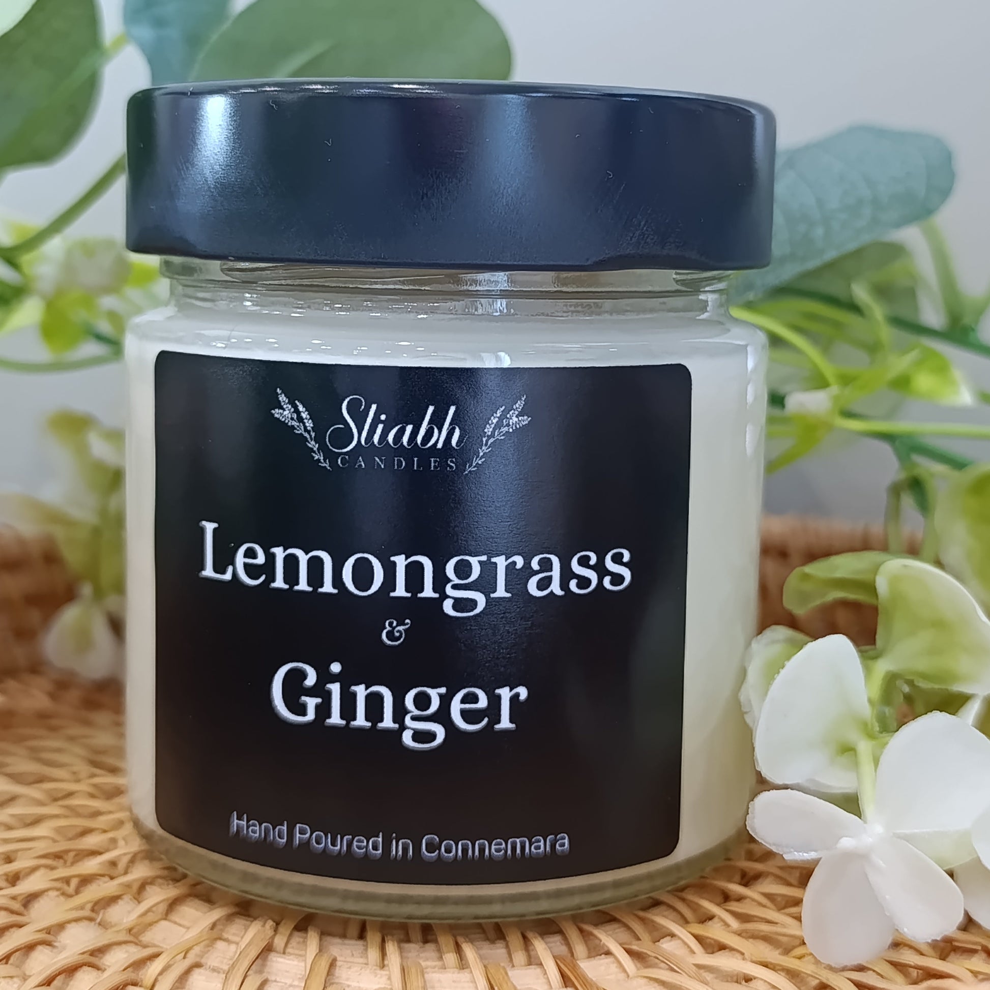 Jar of 'Lemongrass & Ginger' candle with a black lid on a woven surface.