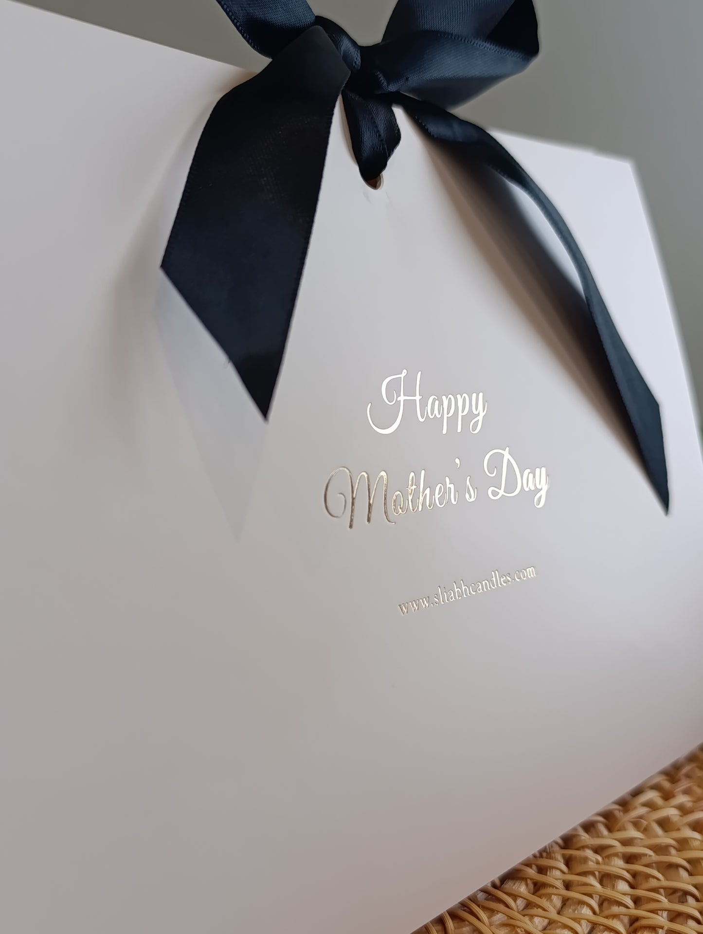 White box with a black ribbon and 'Happy Mother's Day' text on a neutral background
