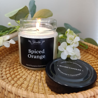 Spiced Orange candle in a glass jar with a black lid on a woven surface.